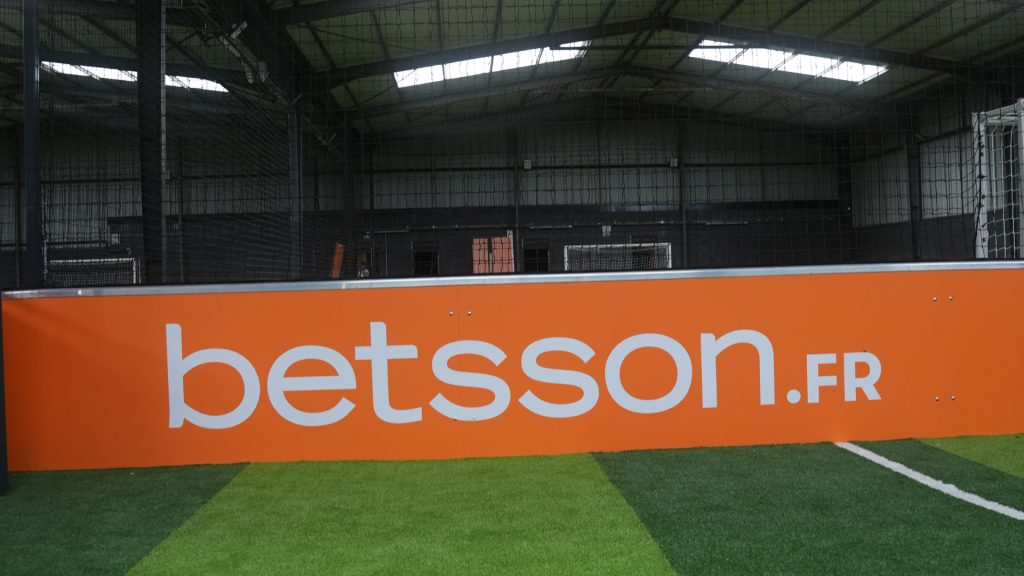 Bannière-publicitaire-de-la-marque-Betsson-orange-et-blanche,-partenaire-de-l'enseigne-Urban-Soccer.