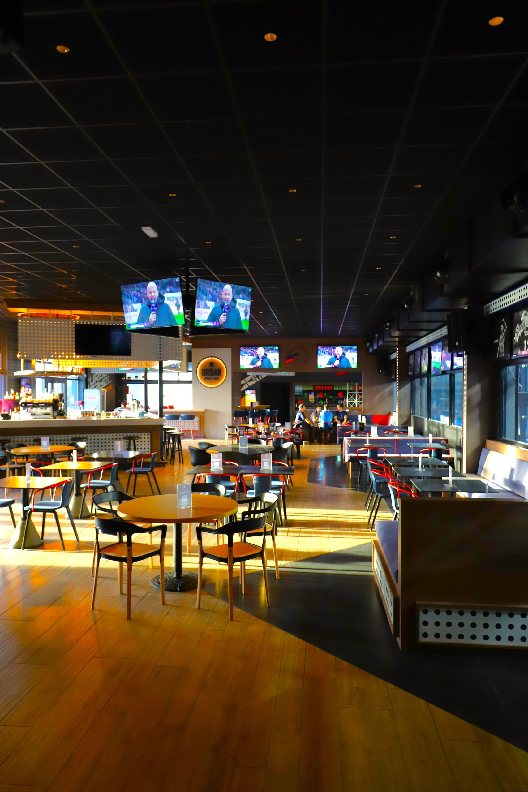 Vue intérieure du restaurant Urban Soccer avec écrans diffusant un match, espace lumineux et tables modernes, photographie réalisée par Clap Agency.